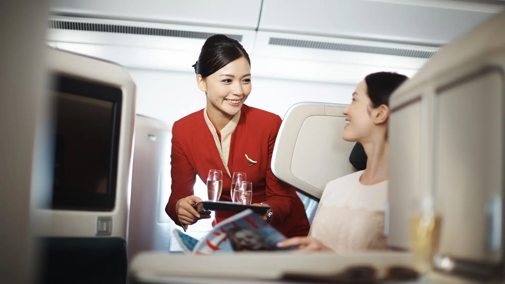 A woman in cathay pacific in businessclass seats serving water