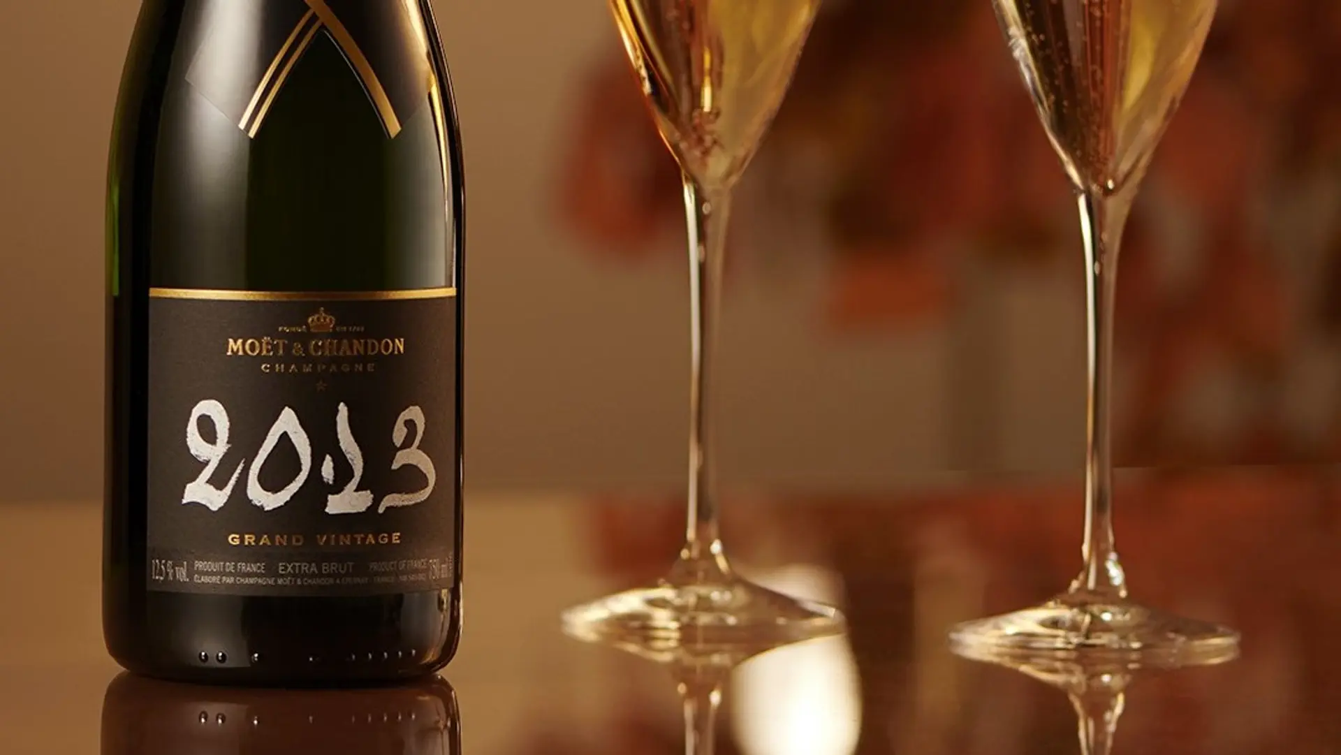 A MOET å CHANDON 2023 model at a table with two glasses